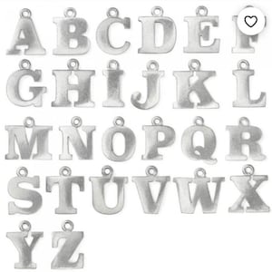 Puede incluir: Un conjunto de colgantes de alfabeto plateados, cada uno con un lazo para sujetar a joyas u otras manualidades. Se muestran las letras de la A a la Z, mostrando una variedad de fuentes y estilos. Ideal para accesorios personalizados.