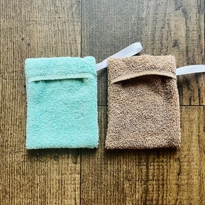 Puede incluir: Dos esponjas de ba&ntilde;o, una azul claro y otra marr&oacute;n, con cordones blancos. Las esponjas est&aacute;n hechas de un tejido suave y texturizado.