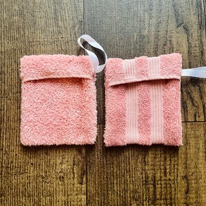 Puede incluir: Dos salvadores de jab&oacute;n de rizo rosa con lazos de cinta blanca. Uno es liso y el otro tiene rayas rosas.