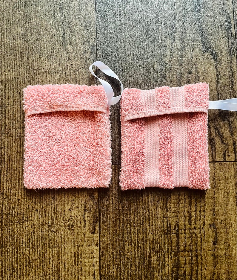 Puede incluir: Dos salvadores de jab&oacute;n de rizo rosa con lazos de cinta blanca. Uno es liso y el otro tiene rayas rosas.