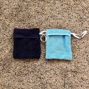 Puede incluir: Dos peque&ntilde;as toallitas rectangulares, una azul marino y otra azul claro, est&aacute;n sobre una alfombra de pelo marr&oacute;n.