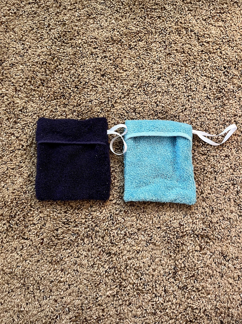 Puede incluir: Dos peque&ntilde;as toallitas rectangulares, una azul marino y otra azul claro, est&aacute;n sobre una alfombra de pelo marr&oacute;n.