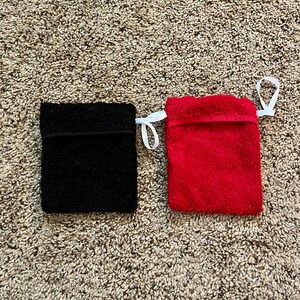 Puede incluir: Dos peque&ntilde;as bolsas rectangulares de tela con cordones de ajuste blancos. La bolsa de la izquierda es negra y la de la derecha es roja.
