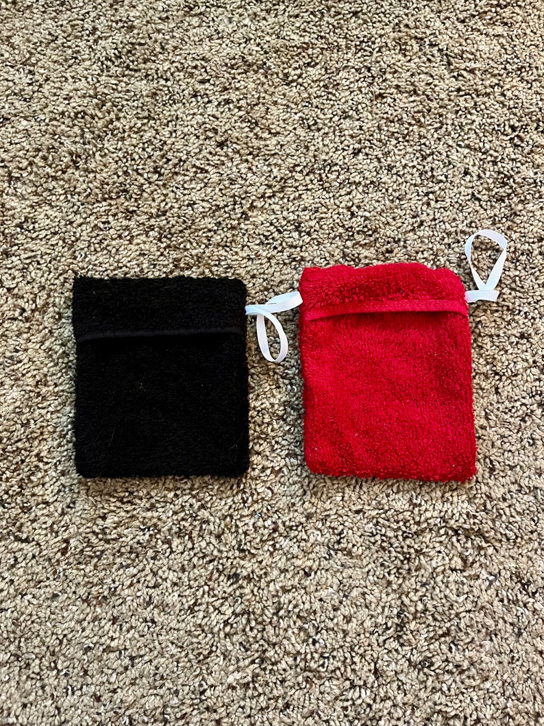 Puede incluir: Dos peque&ntilde;as bolsas rectangulares de tela con cordones de ajuste blancos. La bolsa de la izquierda es negra y la de la derecha es roja.