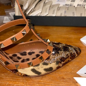 May include: Brown leather high-heeled sandals with gold studs and a leopard print fabric. The sandals have a size tag that reads "35 2 40".