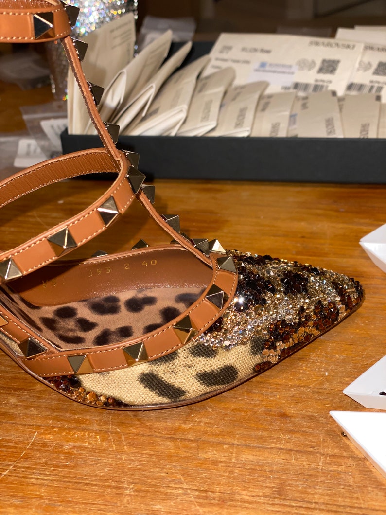 May include: Brown leather high-heeled sandals with gold studs and a leopard print fabric. The sandals have a size tag that reads "35 2 40".