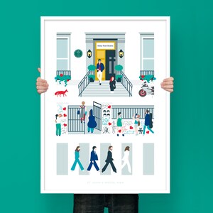 Puede incluir: Una ilustración enmarcada en blanco de los estudios Abbey Road en Londres, Inglaterra. La ilustración presenta un edificio con una puerta amarilla y un letrero que dice "Abbey Road Studios". Hay personas caminando por un paso de cebra, un zorro rojo y una motocicleta. El texto en la parte inferior de la ilustración dice "St. John's Wood, NW8".