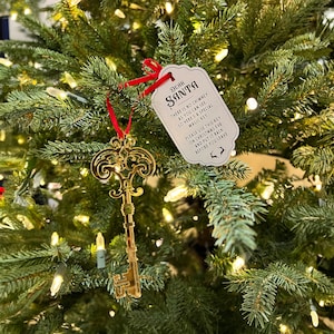 May include: A gold key ornament hangs on a Christmas tree with a white tag that reads "Dear Santa, There is no chimney as you can see so here's a special magic key. Please use this key on Christmas Eve and put it back before you leave."