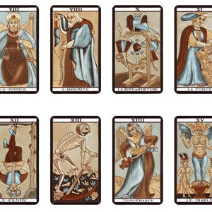 May include: Eight tarot cards arranged in two rows, featuring illustrations labeled La Justice, L'Hermite, La Roue de Fortune, La Force, Le Pendu, XIII, Temperance, and Le Diable. Each card displays a unique figure or symbol in muted tones.