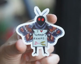 May include: A black and red moth with large wings holding a sign that says "I love lamp ramps". The moth has red eyes and is holding the sign with its front legs.