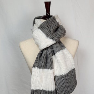 May include: A gray and white striped knitted scarf. The scarf is folded and displayed on a mannequin.