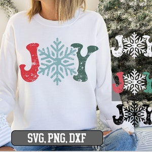 May include: White sweatshirt with the word "JOY" in red and green, with a snowflake in the center. The sweatshirt has a distressed, vintage look. The image also includes the text "SVG, PNG, DXF".