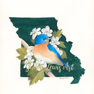 May include: A watercolor painting of a bluebird perched on a branch with white flowers. The bird is in the center of the painting, and the flowers are around it. The background is a green outline of the state of Missouri.