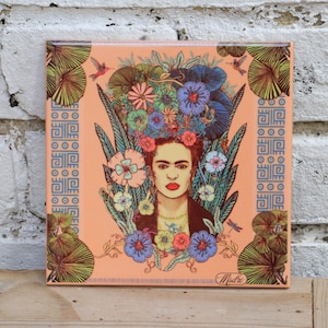 May include: A square ceramic tile with a colorful illustration of Frida Kahlo surrounded by flowers and leaves. The tile has a peach background and a blue and white geometric border.