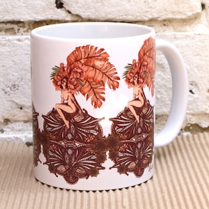 Peut inclure: Une tasse en céramique blanche avec un motif de deux femmes portant des coiffures élaborées en plumes et fleurs. Les femmes sont assises sur une base à motifs avec des détails complexes. La tasse est décorée dans des tons de brun et d'orange.