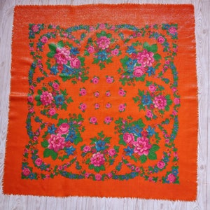 May include: A bright orange square scarf with a floral pattern in shades of pink, blue, and green. The scarf has a fringed edge.