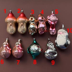 Puede incluir: Una colección de diez adornos navideños vintage. Los adornos incluyen diseños de hongos, búhos, monos, peces y Papá Noel. Los adornos están hechos de vidrio y presentan una variedad de colores, incluyendo rojo, plata, rosa y verde.
