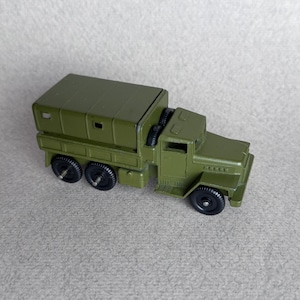 Peut inclure: Un camion militaire jouet vert avec une benne en toile et des roues noires.