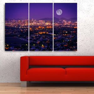 May include: A panoramic view of a city skyline at night with a large, bright moon in the sky. The city lights are visible in the distance, and the buildings are silhouetted against the purple sky.