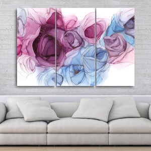 May include: Triptych canvas art featuring abstract floral designs in shades of purple, pink, and blue. The artwork is displayed above a white sofa in a modern living room setting. The background is a white brick wall.