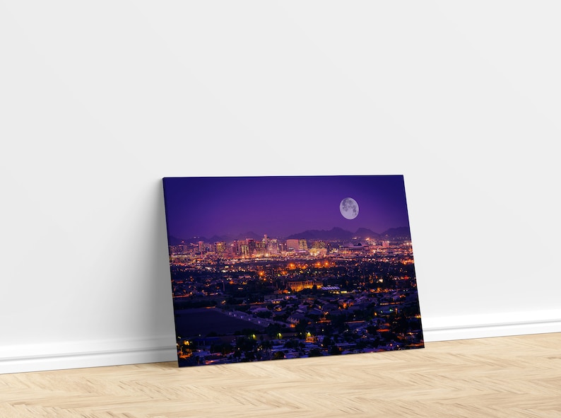 May include: A nighttime cityscape with a full moon in the sky. The city is lit up with lights, and the buildings are silhouetted against the purple sky.