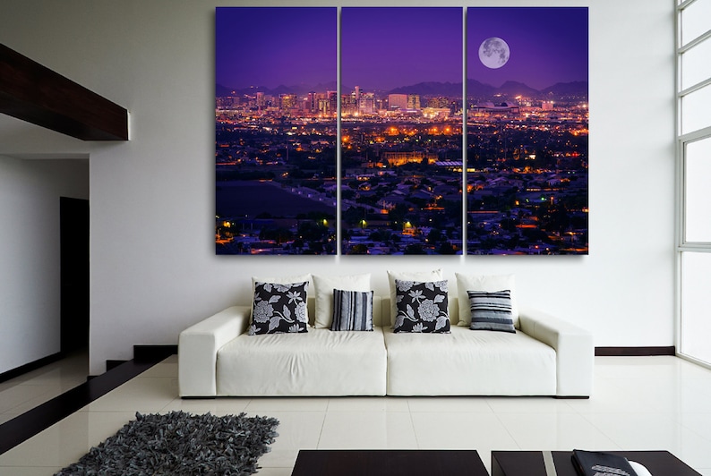 May include: A panoramic view of a city skyline at night with a large, bright moon in the sky. The city is lit up with lights, and the buildings are silhouetted against the purple sky.