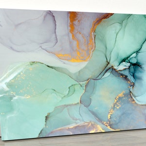 May include: Abstract art canvas print featuring flowing watercolor-style designs in shades of teal, gold, and gray. The artwork has a modern aesthetic, with fluid shapes and metallic accents. The canvas is stretched and ready to hang.