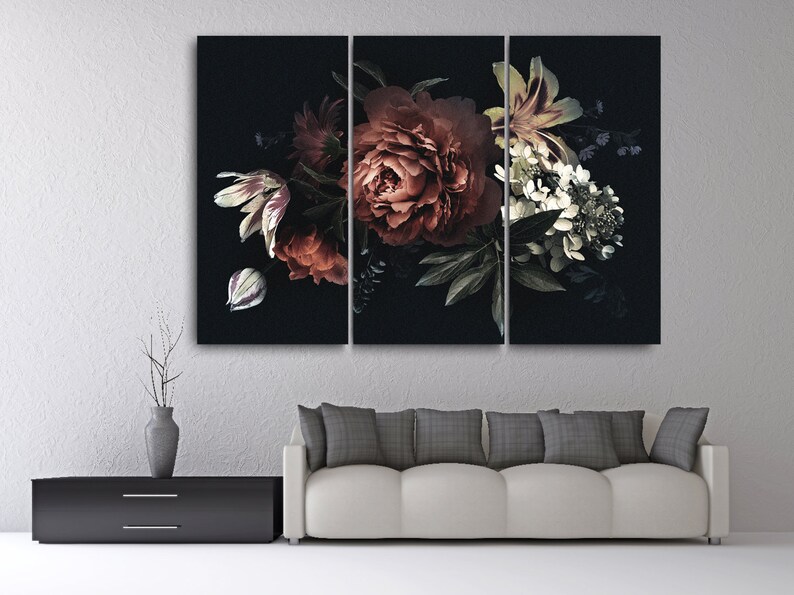Op de afbeelding: Een drieluik canvas print met een donker bloemstuk. Het kunstwerk toont een boeket bloemen in tinten rood, wit en groen tegen een zwarte achtergrond. Het arrangement omvat pioenrozen, tulpen en andere bloemen.