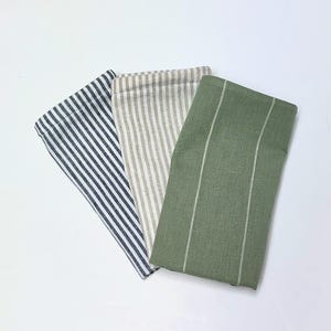 May include: Three striped kitchen towels, one in blue and white, one in beige and white, and one in green and white.