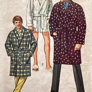 May include: Illustration of three bathrobes in different patterns. One is white, another is a plaid pattern in green and yellow, and the third is burgundy with a white paisley design. Each robe has a matching belt and pockets.