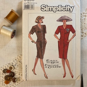May include: Simplicity sewing pattern number 8483 for sizes 10, 12, and 14. The pattern includes instructions for making a dress with a button-up front and short sleeves. The pattern is labeled "Easy to Sew" and "Facile a Coudre".