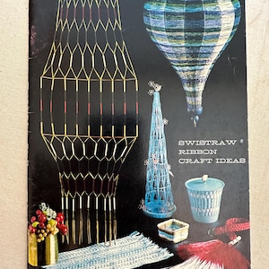 May include: A book titled "Swistraw Ribbon Craft Ideas" by LeJeune W. Griffith. The cover features a variety of colorful crafts made with ribbon, including a hot air balloon, a hanging lamp, a Christmas tree, and a woven rug.