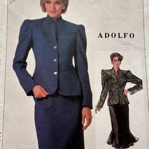 May include: Vintage ADOLFO pattern featuring a navy blue suit with a high collar jacket and matching skirt. The pattern includes a smaller illustration of a black and gold jacket and skirt. Text includes "cut skirt seam wider".