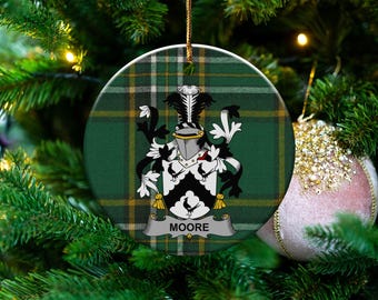 Könnte beinhalten: Runder Weihnachtsschmuck mit einem grün-gelben Karomuster. Der Schmuck zeigt ein Familienwappen mit schwarzen, weißen und goldenen Details und den Namen "MOORE" auf einem Banner. Der Anhänger hängt an einer goldenen Schnur.