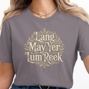 Gray t-shirt with "Lang May Yer Lum Reek" text in ornate gold lettering.