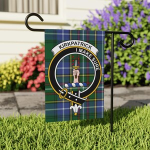 May include: A rectangular garden flag featuring a blue, green, and white plaid tartan pattern. Centered is a black circular belt emblem with gold trim, containing a hand holding a dagger with red droplets and the text KIRKPATRICK I MAKE SURE.