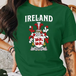 May include: Green t-shirt with a white crest featuring a red and white shield with a gold crown and the text "IRELAND CLANCY".