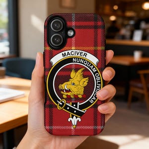 May include: A phone case with a red and black tartan design. It displays a circular emblem with a yellow boar, the name "MACIVER", and the motto "NUNQUAM OBLIVISCAR". The case is held in a hand.