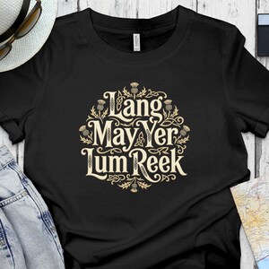 Black t-shirt with "Lang May Yer Lum Reek" in ornate lettering and thistle accents.