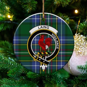 May include: Round Christmas ornament with a green, blue, and yellow plaid pattern. The ornament features a crest with a red rooster and the words "LAING" and "VIGILANCE". A gold string is attached for hanging.