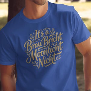 Blue t-shirt with gold Celtic knot lettering that reads "It's a Braw Bricht Moonlight Nicht".