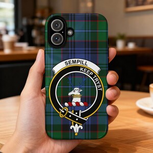May include: A smartphone case with a green, blue, and red tartan design. The case displays a circular emblem with a deer, the words "SEMPILL" and "KEEP TRYST". The case is held in a hand.
