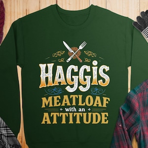 Może przedstawiać: Zielony sweter z nadrukiem graficznym, który głosi "Haggis Meatloaf with an Attitude". Grafika przedstawia skrzyżowany nóż i widelec z gałązką zieleni.