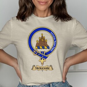 Cream t-shirt with a blue circular crest featuring a goat and text.