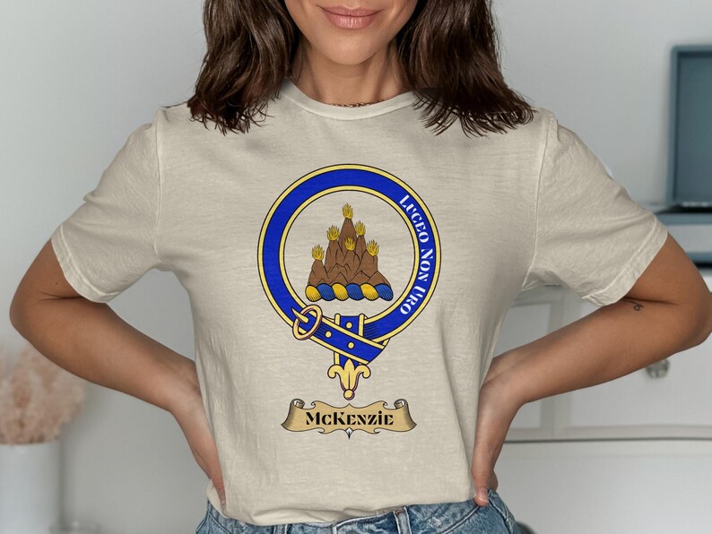 Cream t-shirt with a blue circular crest featuring a goat and text.