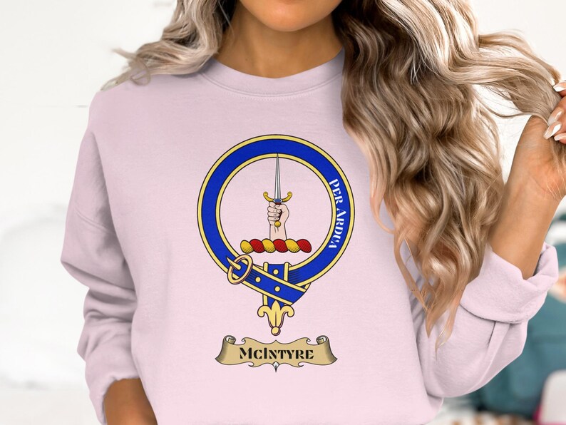 Light pink crewneck sweatshirt with McIntyre clan crest featuring a dagger and Latin motto.