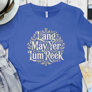 Blue t-shirt with "Lang May Yer Lum Reek" text in ornate gold lettering.