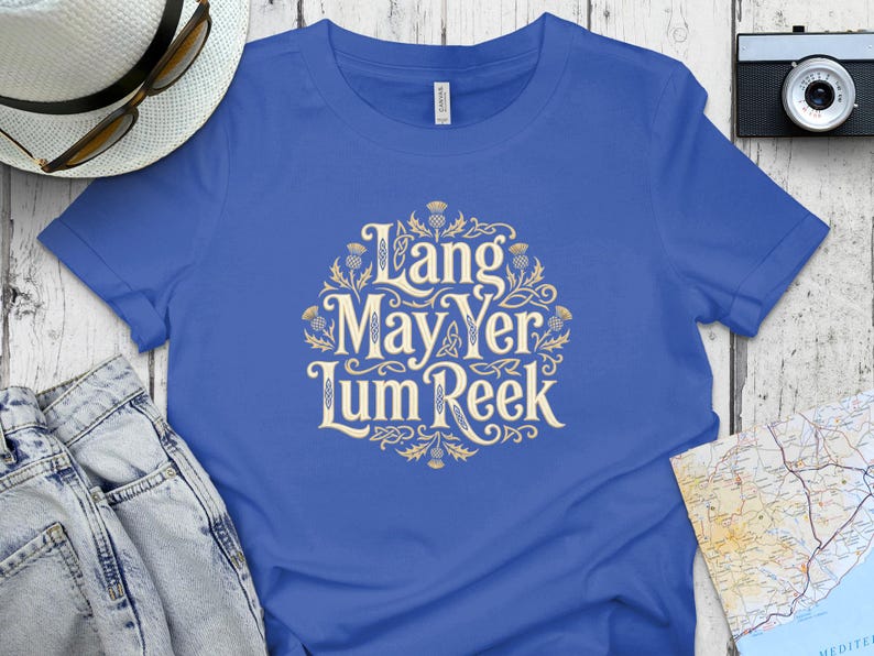 Blue t-shirt with "Lang May Yer Lum Reek" text in ornate gold lettering.