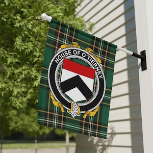 Könnte beinhalten: Eine rechteckige Gartenflagge mit einem grünen, schwarzen und gelben Schottenkaro-Muster. In der Mitte befindet sich ein kreisförmiges schwarzes Gürtel-Emblem mit dem weißen Text "HOUSE OF O'TIERNEY", das einen in rot, weiß und schwarz unterteilten Schild umschließt.