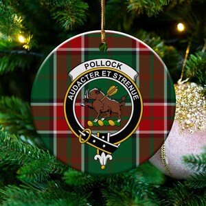 May include: Round Christmas ornament with a green, red, and brown plaid pattern. The ornament features a crest with the name "POLLOCK" and the motto "AUDACTER ET STRENUE". A brown animal with a yellow arrow is in the center.